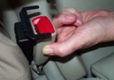 Hand holding a car seat belt receiver with alarm attached
